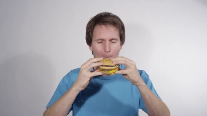 肖像: 饥饿的高加索人咬了一个美味的双层芝士汉堡。