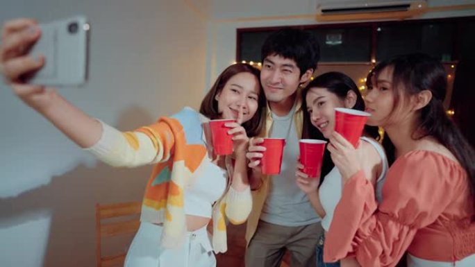 年轻的亚洲朋友在私人聚会上喝酒和吃零食时自拍。
