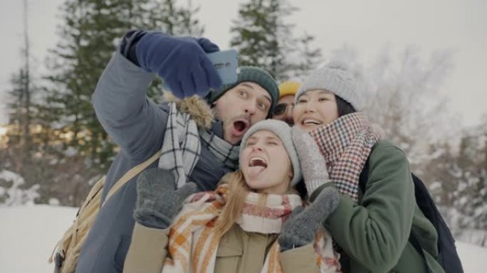 在冬季森林中站立的智能手机相机拍照的游客群体多样化