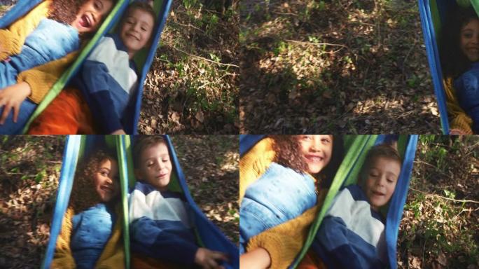 小孩子在吊床上摇摆，在树林里玩得开心