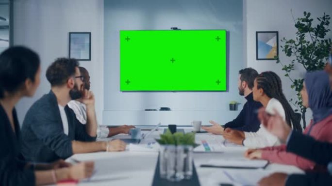 现代多民族办公室会议室会议: 成功的经理，高管组成的多元化团队使用绿屏色键电视，庆祝并为成功的电子商