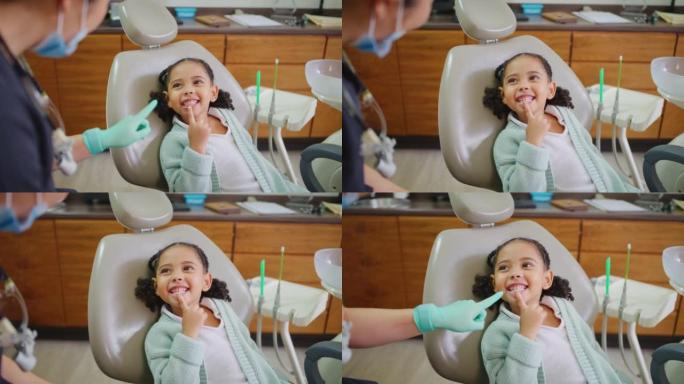 儿科牙医与孩子的联系，通过在咨询过程中使其有趣或有趣来解释牙科手术。友好可爱的小女孩学习健康的牙齿和