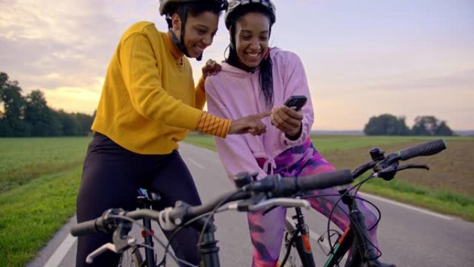 手持慢动作的两名中年女性看着智能手机，站在高速公路的一侧