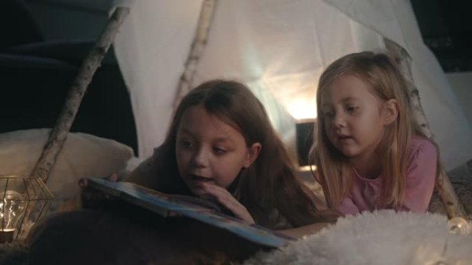 姐姐在帐篷里给妹妹读故事