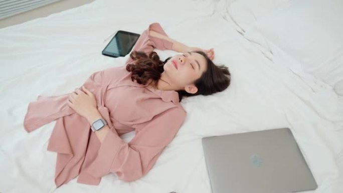 筋疲力尽的女人躺在床上睡着了，无线设备。