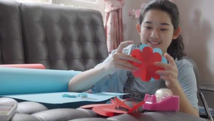 CU: 亚洲年轻少女制作手工物品护理包。可爱的女孩打包一个包装箱，准备从远处寄给她的家人或朋友。