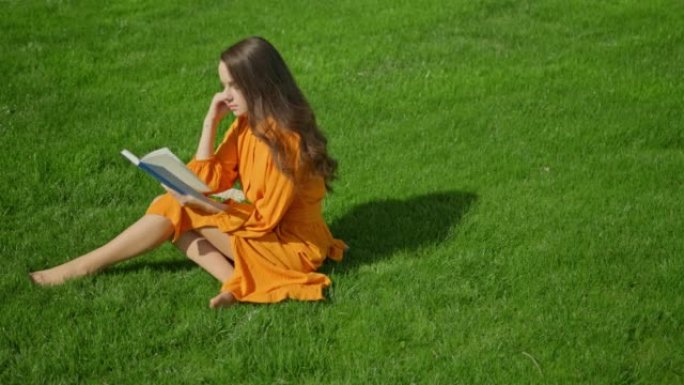 年轻女子坐在草地上看书
