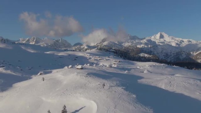 空中: 在阳光明媚的冬日，飞离一个满是小屋的山村。