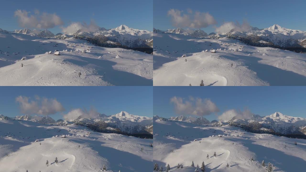 空中: 在阳光明媚的冬日，飞离一个满是小屋的山村。