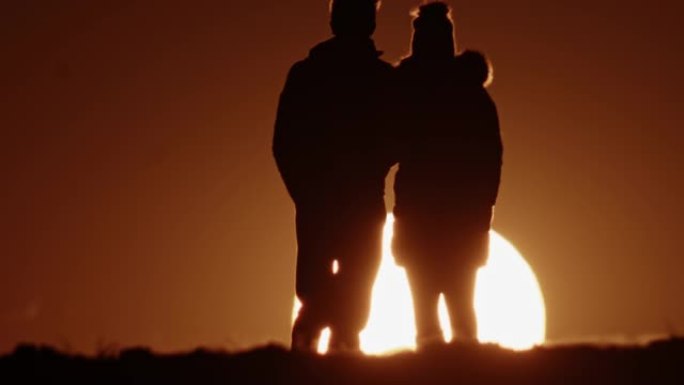 剪影中的SLO MO LS夫妇在日落时欣赏美景