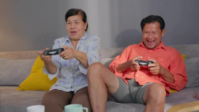 亚洲高级男子在家里的客厅里与高级女子一起玩电子游戏后感到高兴