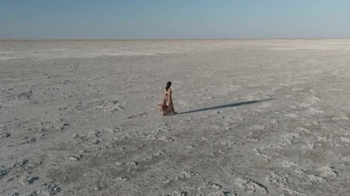 博茨瓦纳壮观的Makgadikgadi Pans广阔的空间中行走的一位穿着漂亮衣服的女人的特写鸟瞰图