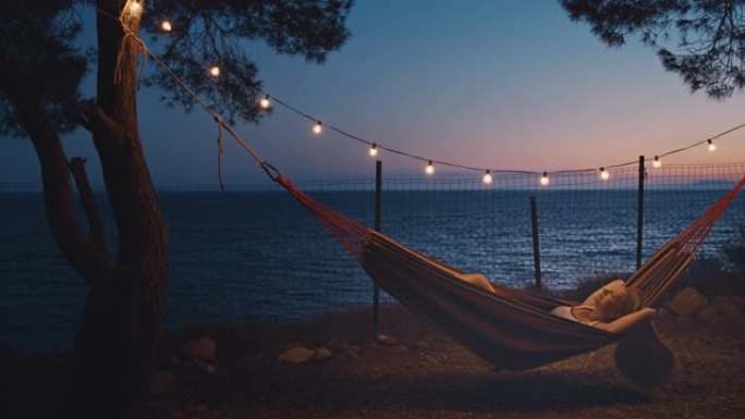 黄昏时，SLO MO女人在夏季露营地的吊床上放松
