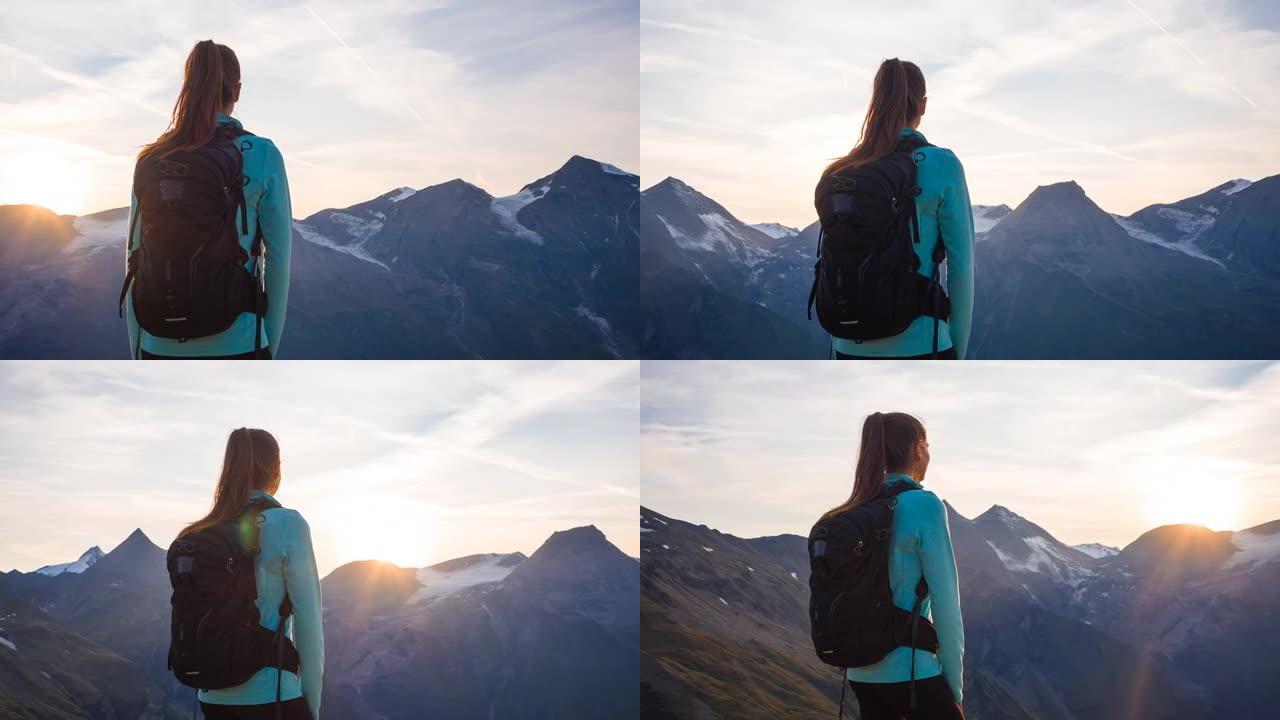 女徒步旅行者站在山顶上，在日落时欣赏山谷的壮丽景色