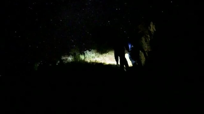 两个徒步旅行的人在夜晚的黑暗山上行走
