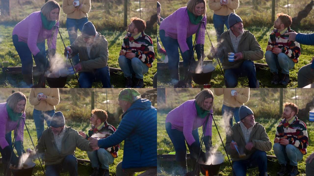 在篝火旁热身外国人农场野餐野炊喝汤保暖