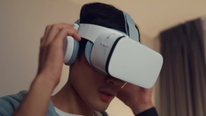 特写年轻的亚洲男子游戏玩家穿灰色连帽衫把虚拟现实oculus放在头上感觉激动人心的乐趣选择功能准备晚