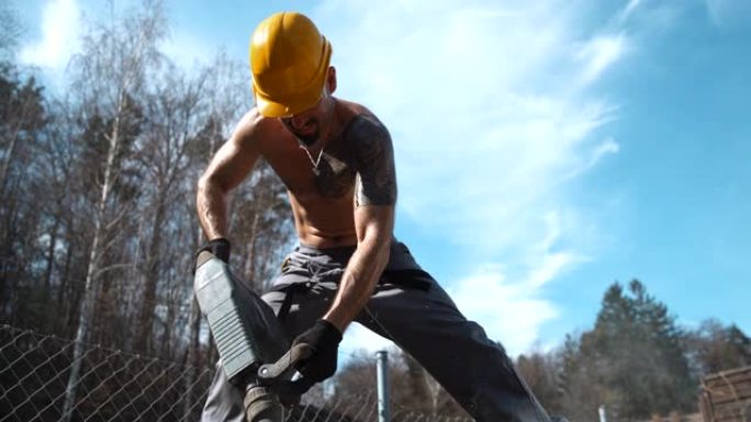 超级SLO MO光着膀子的建筑工人使用手提钻