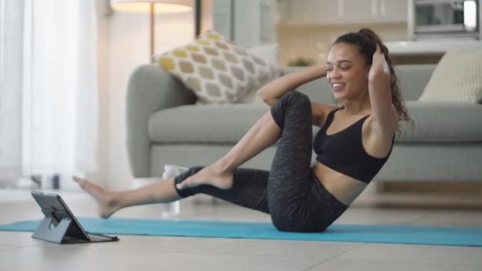 4k视频片段，一名年轻女子在家里进行瑜伽锻炼时使用数字平板电脑