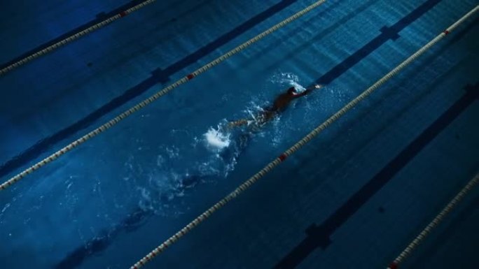 女子游泳运动员在游泳池里比赛。职业运动员决心用蝶式赢得冠军。深色戏剧性的颜色，电影圈车道灯。空中跟踪