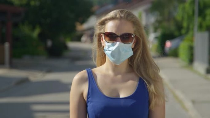 肖像: 年轻的白人妇女戴着太阳镜和浅蓝色的外科口罩。