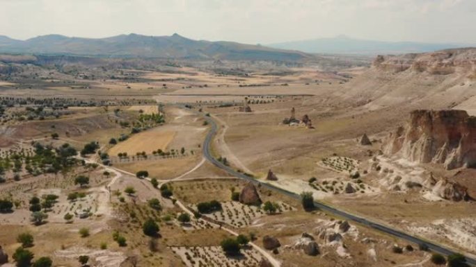 夏天卡帕多西亚土耳其，广阔的阳光明媚的沙漠田野向大山和道路美丽的宽阔空中背景。