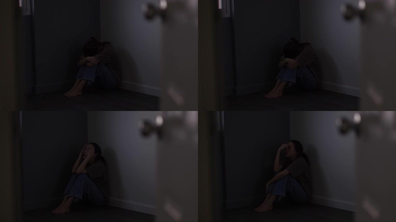 悲伤的年轻女孩躺在黑暗角落的地板上感到悲伤