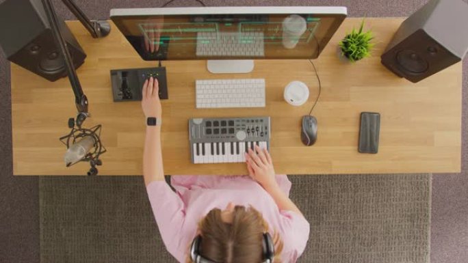 工作室中带有键盘和麦克风的工作站女音乐家的俯视图-慢动作拍摄