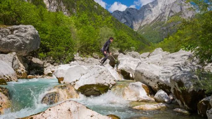 徒步旅行者在山上过河跳过水