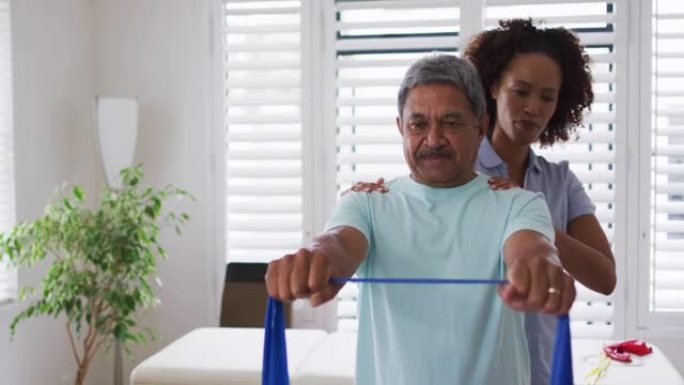 混合种族女理疗师使用锻炼带帮助老年人锻炼
