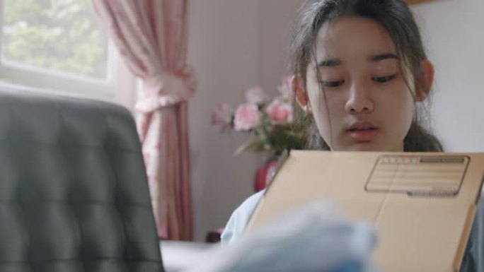 亚洲年轻少女制作手工物品护理包。可爱的女孩打包一个包装箱，准备从远处寄给她的家人或朋友。