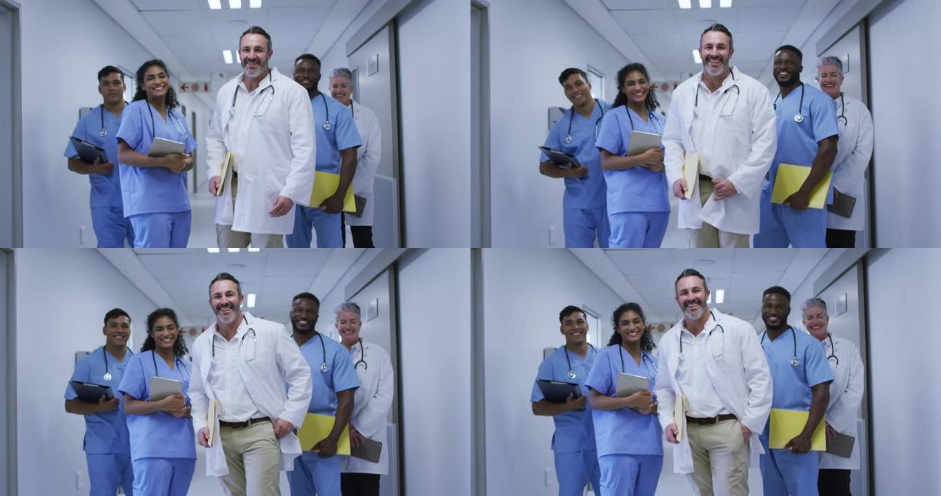 医院走廊上穿着磨砂膏和实验服的微笑男女医生的多元化群体