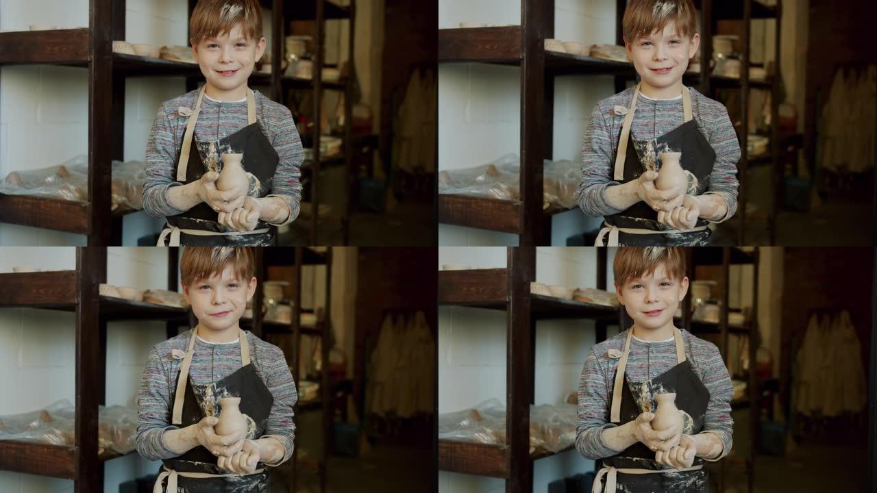 快乐男孩的肖像年轻的波特拿着手工制作的花瓶在车间独自站着微笑