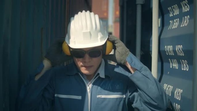 男工人戴上安全耳罩在港口工作前准备慢动作