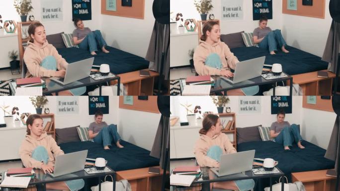 女大学生在笔记本电脑上打字并与室友聊天