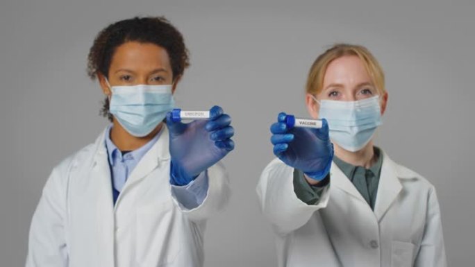 实验室研究人员戴着口罩，手里拿着标有疫苗和欧米克隆的试管