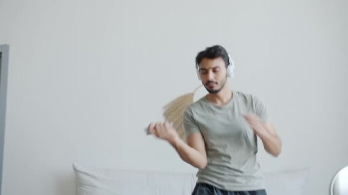 疯狂的中东男子在床上跳舞，通过耳机听音乐