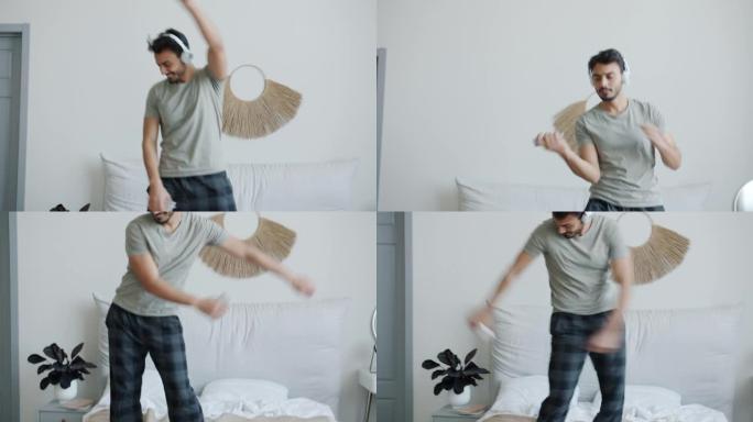 疯狂的中东男子在床上跳舞，通过耳机听音乐