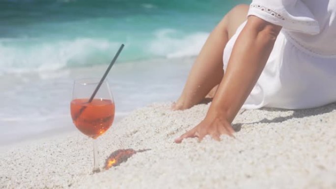 一个女人在海滩上喝鸡尾酒的慢动作视图。