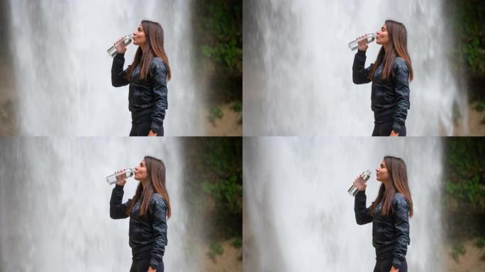 年轻女运动员在瀑布前喝水