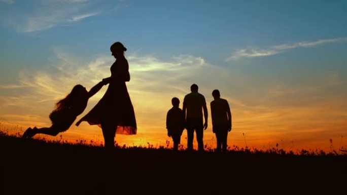 时间扭曲的母亲在黄昏时与两个儿子在草地上散步时旋转女儿