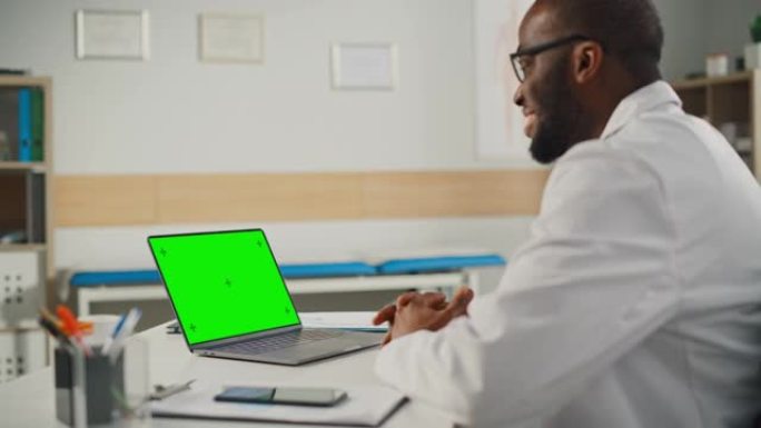医生在线医疗咨询:非裔美国医生正在一台绿屏笔记本电脑上进行视频会议。医护人员向病人解释检查结果。