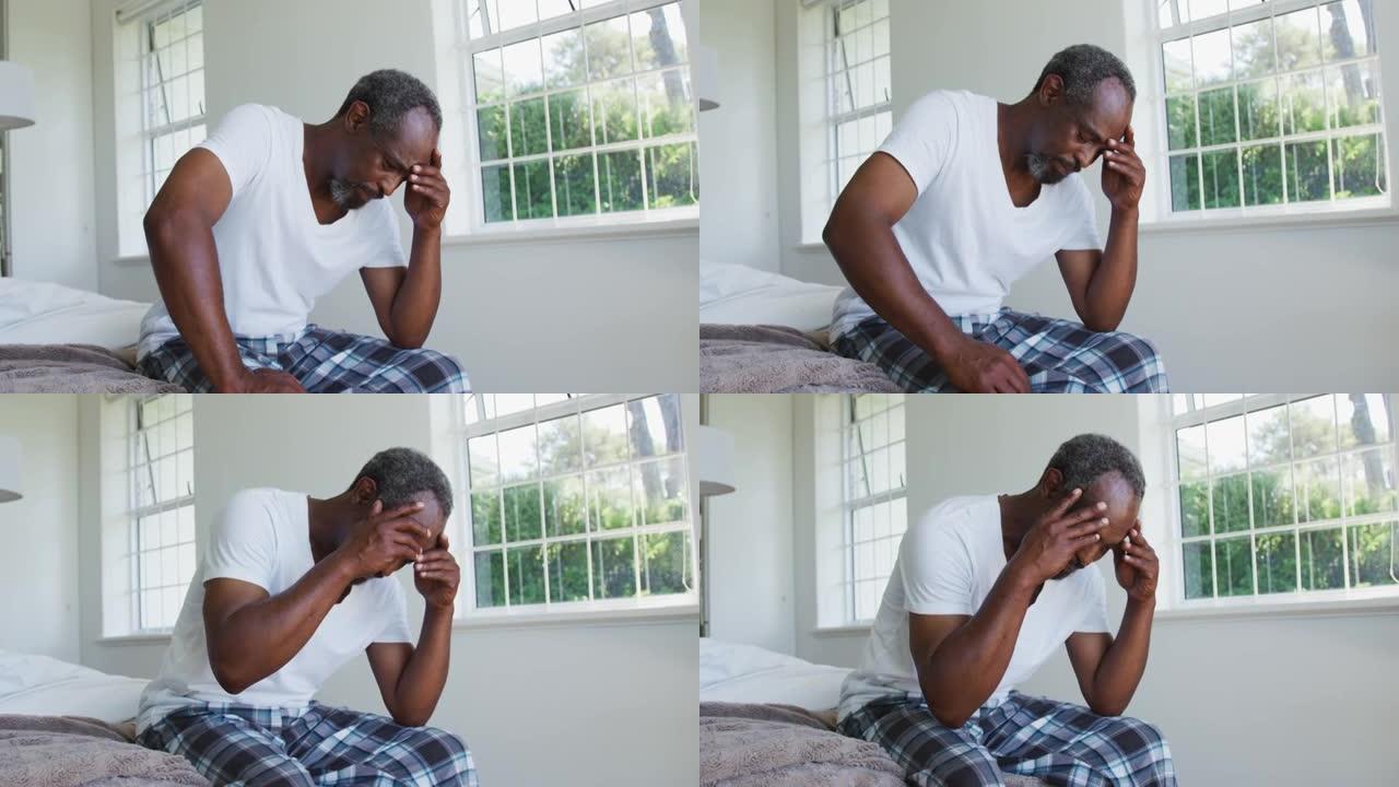 头痛的非裔美国高级男子坐在床上抱着头