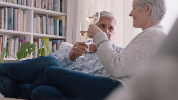 快乐的老夫妻在家沙发上喝酒放松做烤面包庆祝周年纪念享受舒适退休4k镜头中的浪漫关系
