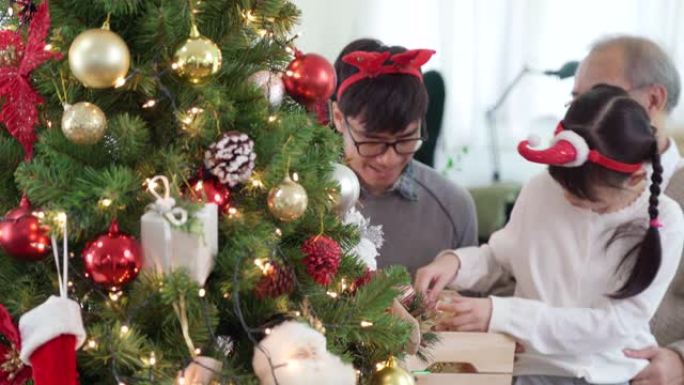 4K UHD向下倾斜多代亚洲快乐家庭装饰圣诞树与装饰品一起为节日快乐冬天做准备。