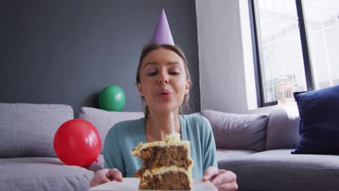 戴党帽的女人在家里的蛋糕上吹蜡烛