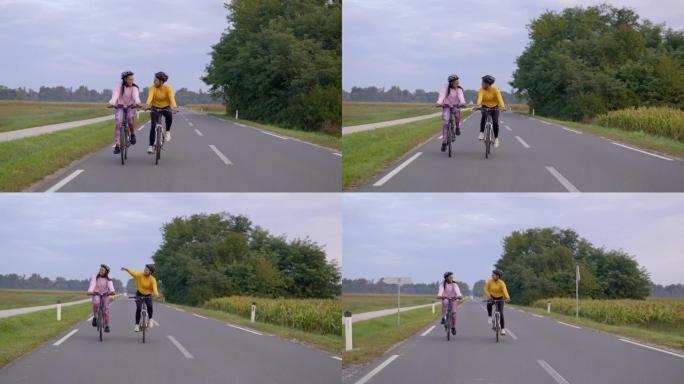 跟踪，手持拍摄两名成年女性在高速公路上快乐地骑行，慢动作