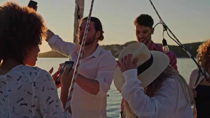 SLO MO一群朋友在日落时在船上的甲板上跳舞时自拍