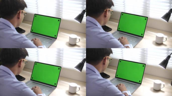 男人在办公室使用带有绿屏的笔记本电脑