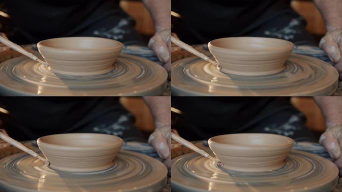 熟练的陶工在投掷轮上装饰漂亮的手工碗的特写镜头